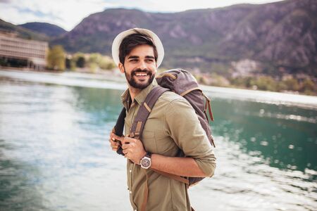 Young man walking by the harbor of a touristic sea resort with boats on backgroundの写真素材