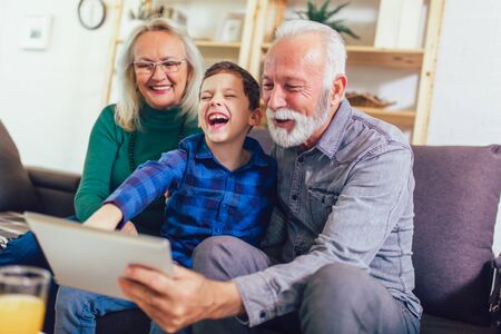 Young boy showing his older grandparents new technologyの写真素材