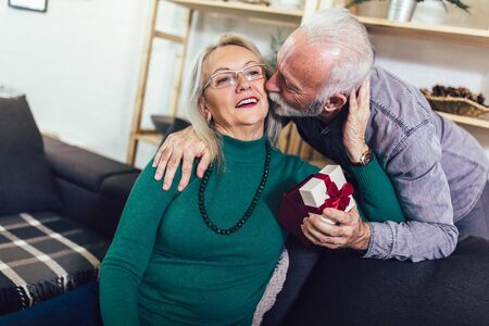 Senior man giving a present to his woman at home.