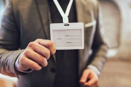Businessman at an exhibition or conference showing a blank security identity name card の写真素材