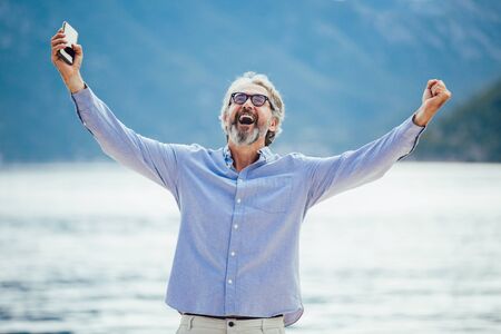 Mature man talking on the smartphone on the marina.の写真素材