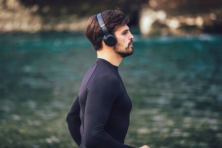 Handsome young man jogging on river bankの写真素材