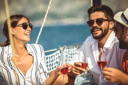 Smiling friends with glasses of champagne on yacht. Vacation, travel, sea, friendship and people conceptの写真素材