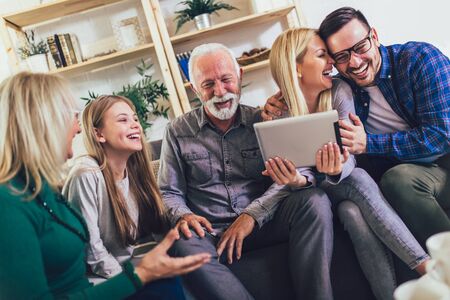 Portrait of a three generation family spending time together at home using digital tablet.の写真素材
