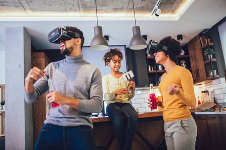 Happy black family at home. Dad, mom and daughter playing virtual reality.