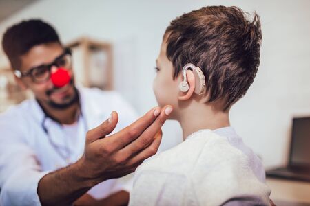Smiling deaf boy with ear implant at doctor's office.の写真素材