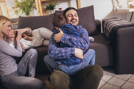 Happy family with kids playing at home. Family sitting on floor and playing together.の写真素材