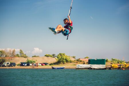 Professional kiter makes the difficult trick on a river. Kitesurfing Kiteboarding action photos man among waves quickly goesの写真素材
