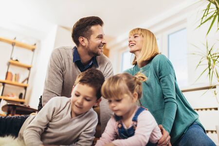 Happy family having fun on floor of in living room at home, laughing. Selective focus.の写真素材