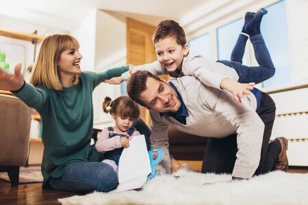 Happy family having fun on floor of in living room at home, laughing. Selective focus.の写真素材