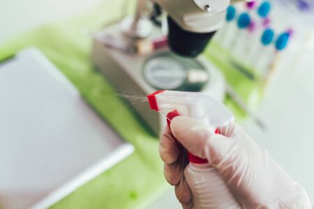 Female disinfecting his lab by spraying a sanitizer from a white bottle