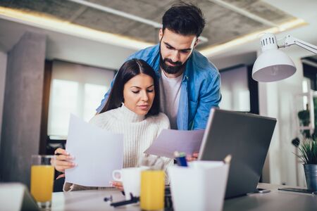 Happy couple doing business together working at home on the laptop.の写真素材