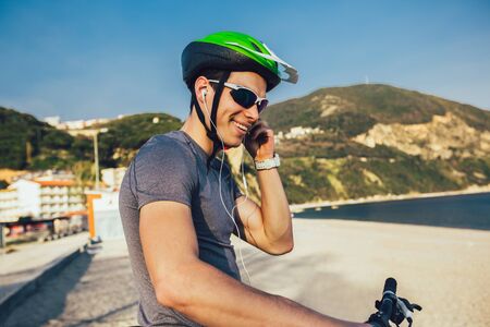 Portrait of mountain biker with helmet and sunglasses listening to music and smiling.の写真素材