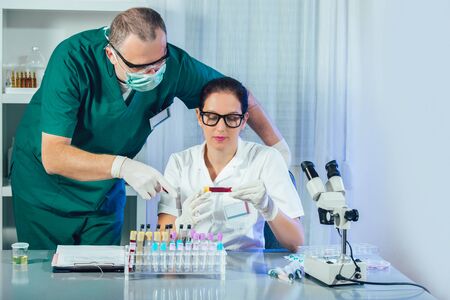 Lab assistants analyzing a blood sample at laboratory. Medical, pharmaceutical and scientific...