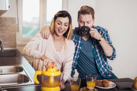 Happy couple make orange juice in morning kitchen and having a good time. の写真素材