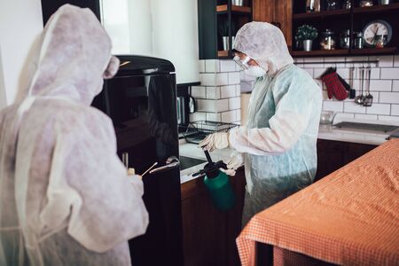 Specialists in protective suits take samples from surfaces in the home to test for a new corona virus.の写真素材