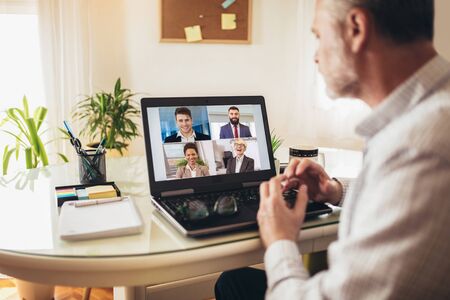 Man working from home having online group videoconference on laptopの写真素材