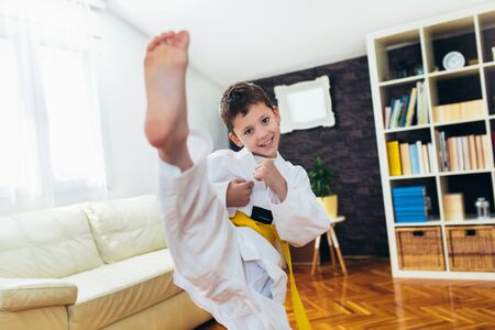 Taekwondo boy exercising at home in living room.の写真素材