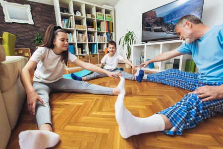 Healthy morning stretching - man with kids doing gymnastic exercise at home