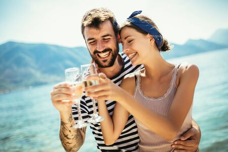 Beautiful couple having fun on the beach, drinking cocktails and smiling.の写真素材