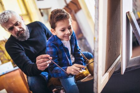 Father and son working and painting together in art studio
