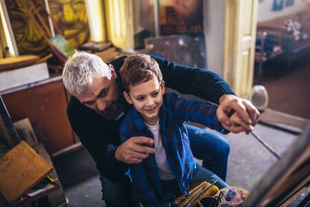 Father and son working and painting together in art studioの写真素材