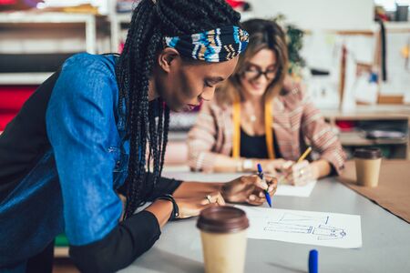 Two young entrepreneur women, or fashion designers working in atelierの写真素材