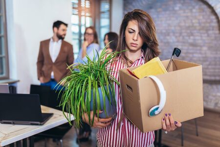 Business woman carrying packing up all his personal belongings and files into a brown cardboard box to resignation in modern office, resign concept.の写真素材