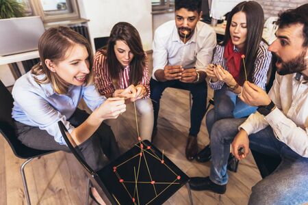 Happy friendly business team having fun at corporate training, funny teambuilding activity, playing spaghetti game.の写真素材