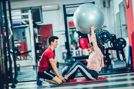 Fit woman working out with trainer at the gym