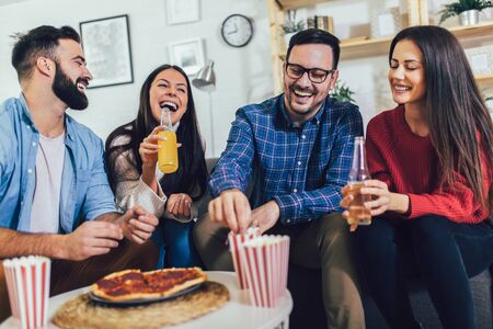 Group of young friends eating pizza in home interior.  Young people having fun together. の写真素材