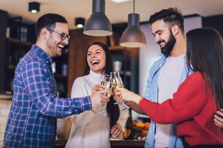 Young people cheering with champagne flutes and looking happy while having home party.の写真素材