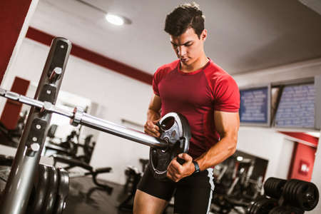 Young handsome man doing exercises in gym