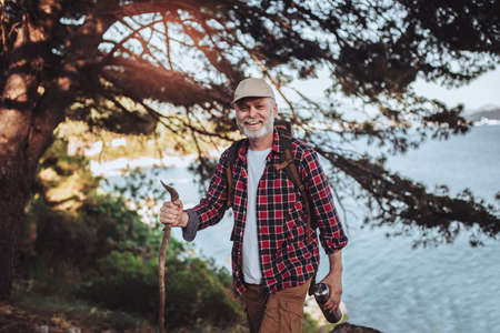 Mature man, hiking by the sea and exploring the nature, at sunset.の写真素材