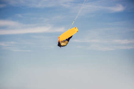 Professional kiter makes the difficult trick on a beautiful background. Kitesurfing Kiteboarding action photos man among waves quickly goesの写真素材