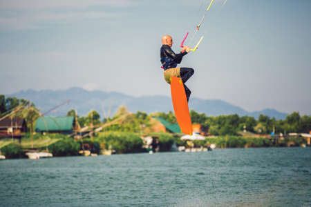 Professional kiter makes the difficult trick on a river. Kitesurfing Kiteboarding action photos man among waves quickly goesの写真素材