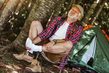 Mature man having injury on his leg on the way to the campの写真素材