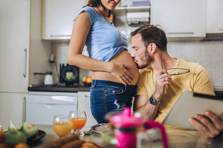 Pregnant woman with husband in the kitchenの写真素材