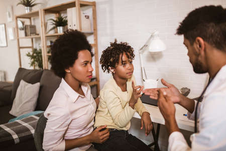Smiling deaf african american girl with ear implant at doctor's office.の写真素材