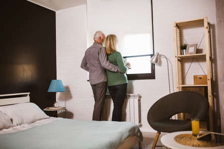 Senior couple holding white mugs at homeの写真素材