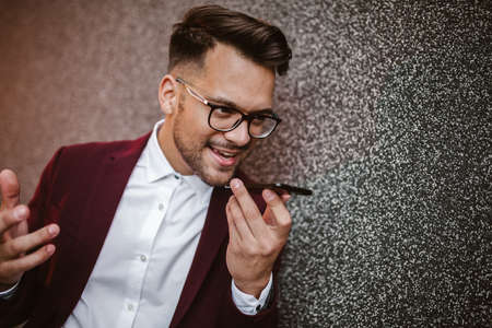 Young business man using voice command recorder on smartphone.の写真素材