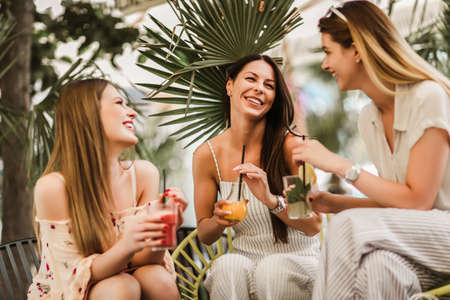 Beautiful girls drinking cocktail in cafe and having fun.の写真素材