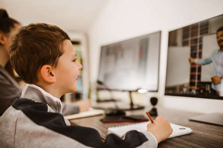 Boy and girl studies at home and doing school homework. Distance learning online education.の写真素材