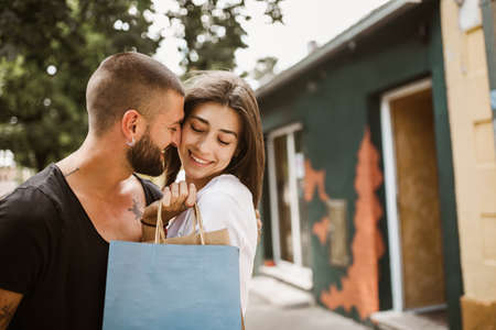 Portrait of happy couple with shopping bags after shopping in city smiling and huging