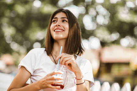 Beautiful girl with a cocktail in hands in the outdoor cafe.の写真素材
