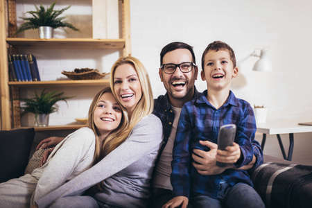 Happy family watching TV together at home and having fun together.の写真素材