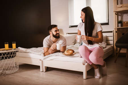 Cute couple having breakfast in bed in the bedroomの写真素材
