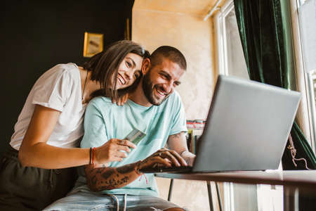 Couple buying online with credit card and laptop in a coffee shop