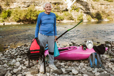 Senior man preparing for kayak tour on a mountain river.の写真素材