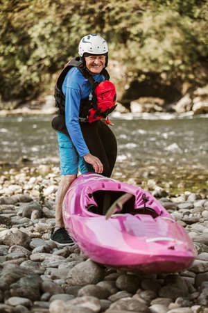 Senior man preparing for kayak tour on a mountain river.の写真素材